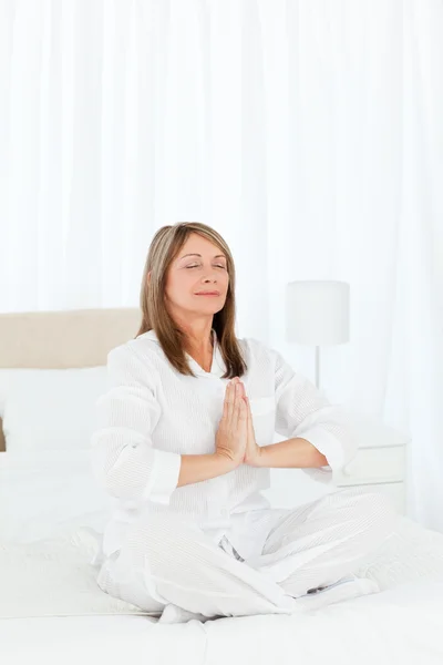 Senior practicing yoga on her bed — Stock Photo, Image
