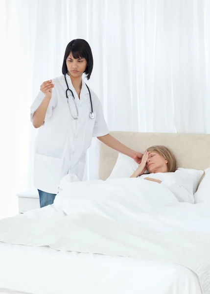 Enfermeira tomando a temperatura de seu paciente — Fotografia de Stock