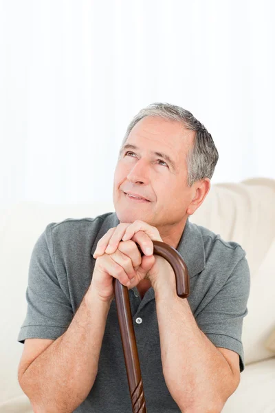 Mature man thoughtful with his walking stick on his bed — Stock Photo, Image