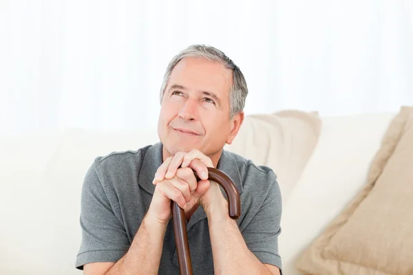 Mature man thoughtful with his walking stick on his bed — Stock Photo, Image