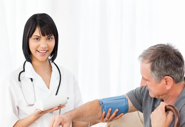Nurse taking blood pressure of her patient — Stock Photo, Image