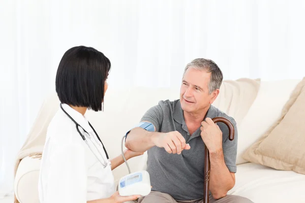 Nurse taking blood pressure of her patient — Stock Photo, Image