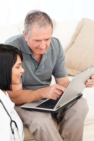 Homme mûr avec son infirmière regardant l'ordinateur portable à la maison — Photo