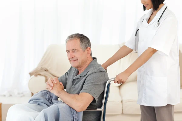 Homem em sua cadeira de rodas com sua enfermeira em casa — Fotografia de Stock