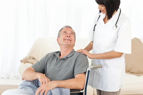 Man in zijn rolstoel met zijn verpleegster thuis — Stockfoto