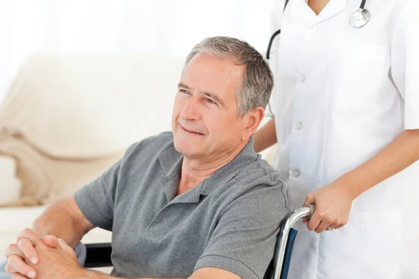 Man in zijn rolstoel met zijn verpleegster thuis — Stockfoto