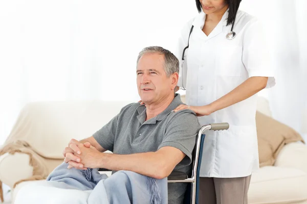 Man in his wheelchair with his nurse at home — Stock Photo, Image