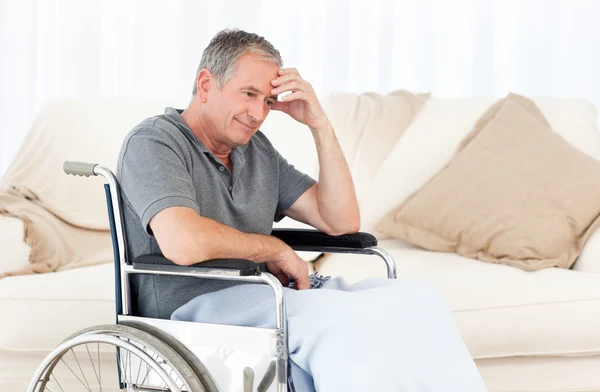 Senior in zijn rolstoel met een hoofdpijn — Stockfoto
