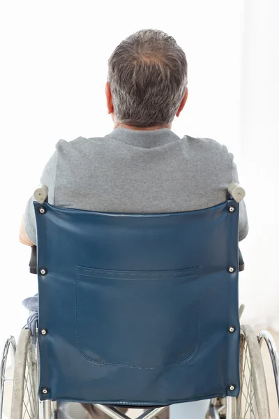 Maturo uomo in la sua sedia a rotelle con la schiena per il fotocamera — Foto Stock