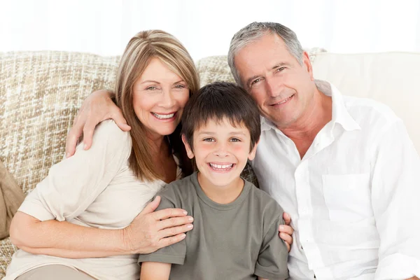 Ein kleiner Junge mit seinen Großeltern, die in die Kamera schauen — Stockfoto