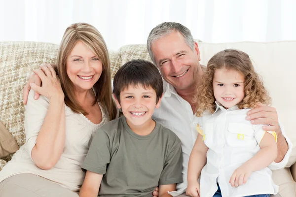 Une famille heureuse sur son canapé regardant la caméra — Photo