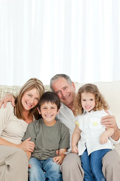 Šťastná rodina na své pohovce, při pohledu na fotoaparát — Stock fotografie