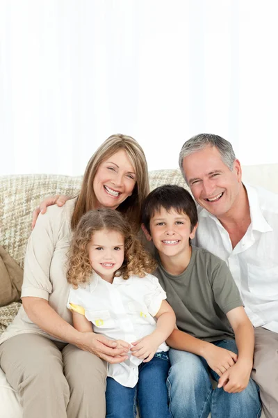 Szczęśliwą rodziną na kanapie, ich patrząc na kamery — Zdjęcie stockowe