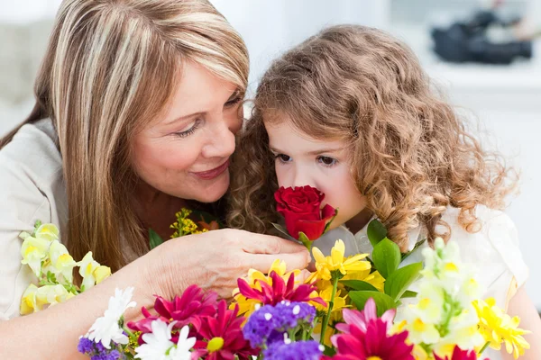 Kleines Mädchen, das Blumen riecht, während ihre Großmutter lächelt — Stockfoto