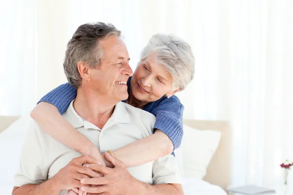 Senior coppia abbracci sul loro letto — Foto Stock