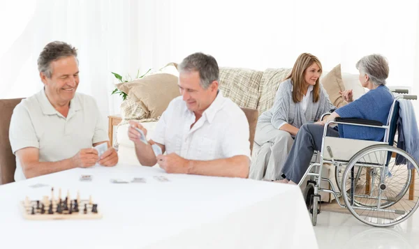 Men playing cards while their wifes are talking — Stock Photo, Image