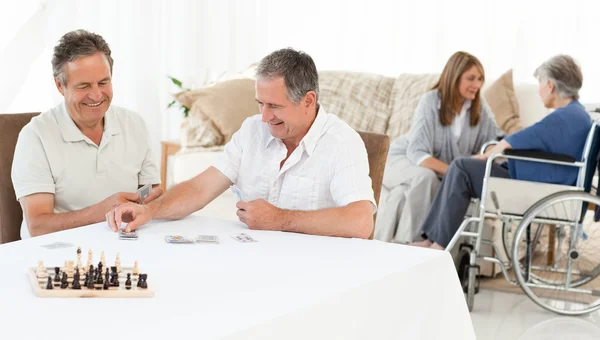 Мужчины играют в карты, пока их жены говорят — стоковое фото