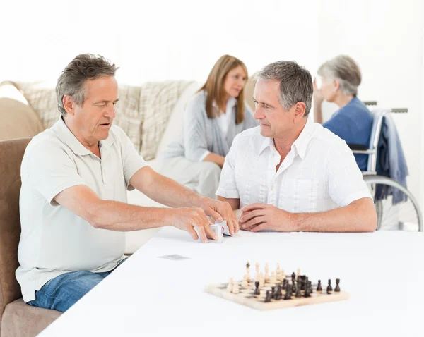 Män spela kort medan deras fruar talar — Stockfoto