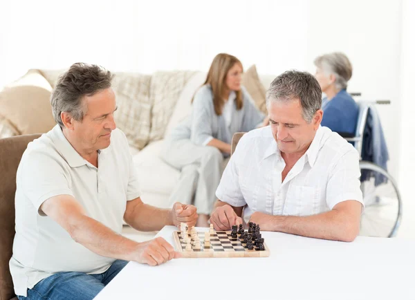 Muži hrají šachy, zatímco mluví jejich manželky — Stock fotografie