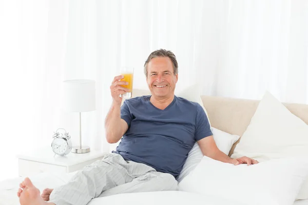 Συνταξιούχος άνθρωπος εξετάζοντας την κάμερα ενώ πίνει oranje ju — Φωτογραφία Αρχείου