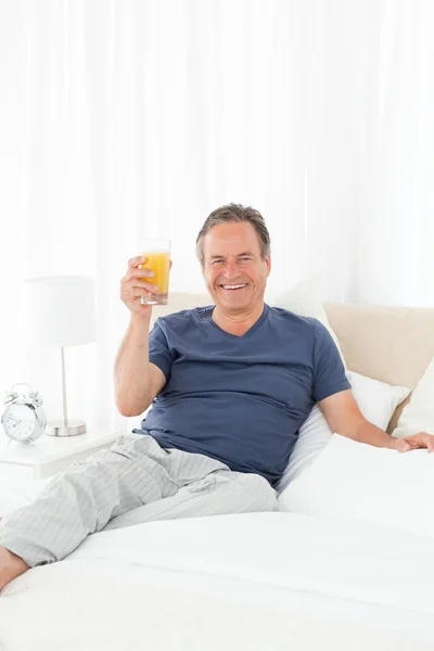Συνταξιούχος άνθρωπος εξετάζοντας την κάμερα ενώ πίνει oranje ju — Φωτογραφία Αρχείου