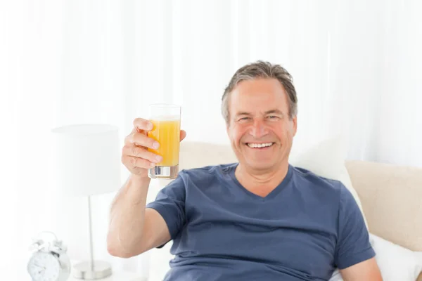 Homem aposentado olhando para a câmera enquanto ele está bebendo oranje ju — Fotografia de Stock