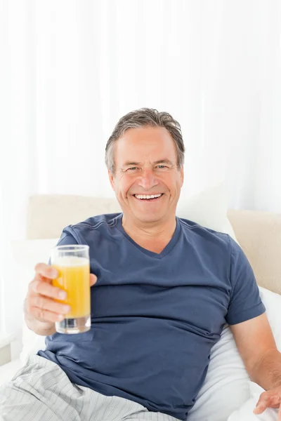 Hombre retirado mirando a la cámara mientras bebe oranje ju —  Fotos de Stock