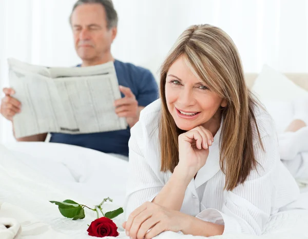 그녀의 남편은 newspap를 읽고는 하는 동안 그녀의 장미와 함께 행복 한 여자 — 스톡 사진