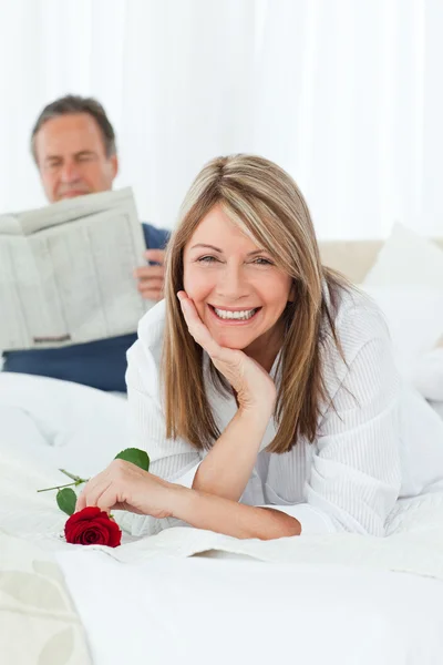 Ευτυχισμένη γυναίκα με το τριαντάφυλλο, ενώ ο σύζυγός της ανάγνωση μια newspap — Φωτογραφία Αρχείου