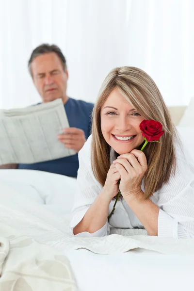 Mulher feliz com sua rosa enquanto seu marido está lendo um boletim informativo — Fotografia de Stock