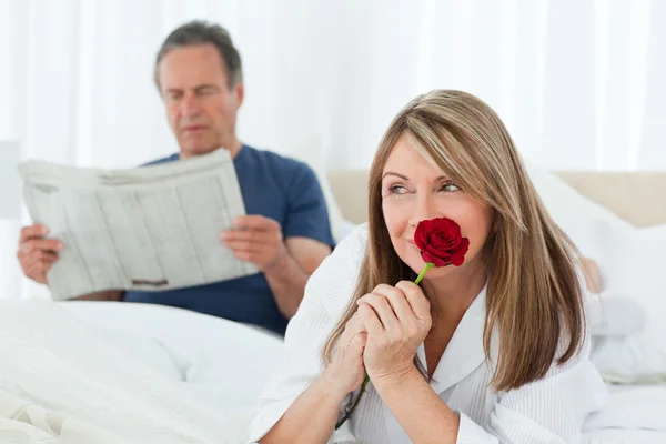 Mujer feliz oliendo su rosa mientras su marido está leyendo una nueva —  Fotos de Stock