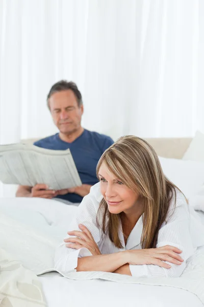 Woman smiling while her husband is reading — Stock Photo, Image