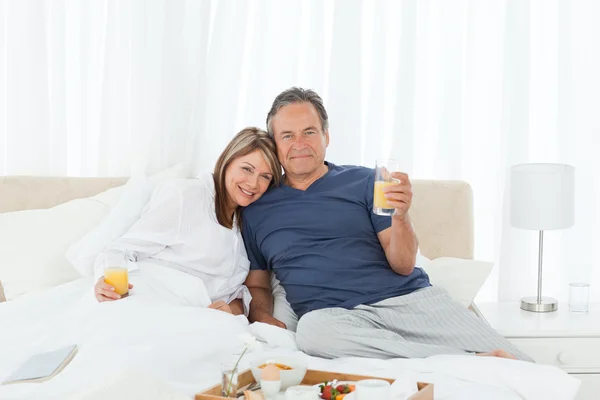Charmant couple prenant le petit déjeuner dans leur lit — Photo