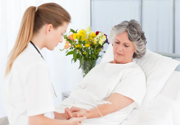 Verpleegkundige een infuus zetten de arm van haar patiëntenfermera cuidando de su paciente — Stockfoto