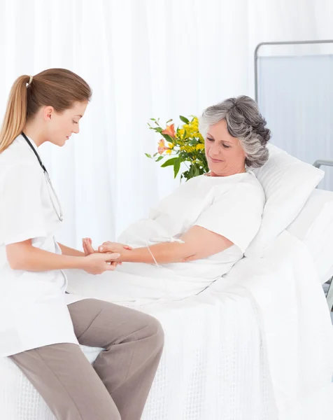 Nurse putting a drip on the arm of her patient — Stock Photo, Image