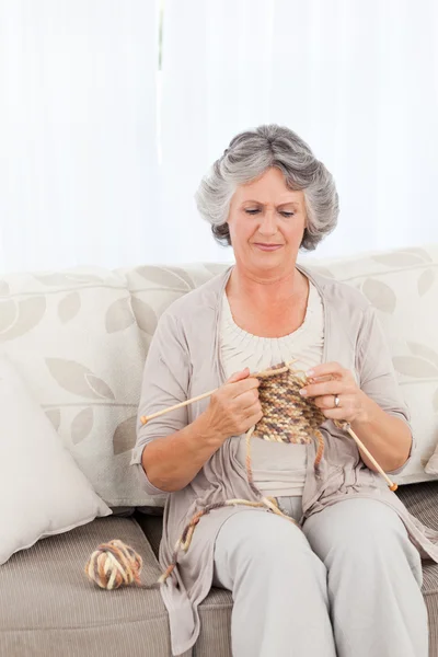 Femme âgée tricotant sur son canapé — Photo