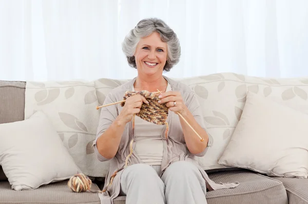 Donna anziana a maglia sul suo divano — Foto Stock