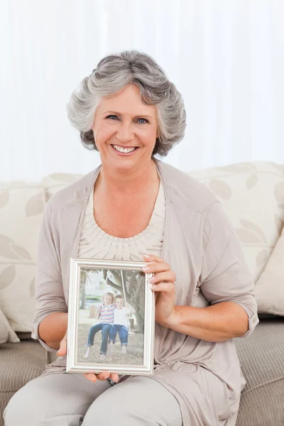 Mulher sorridente mostrando uma foto de seu neto — Fotografia de Stock