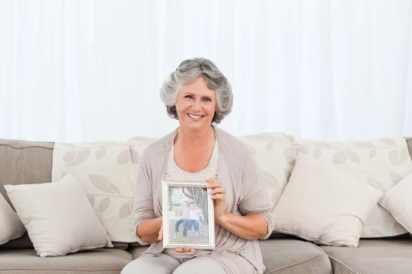 Усміхнена жінка показує фотографію свого онука — стокове фото