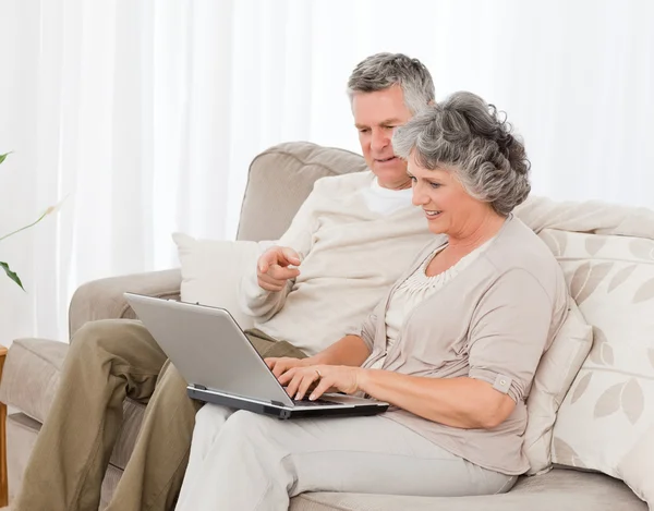 Amantes aposentados olhando para seu laptop — Fotografia de Stock