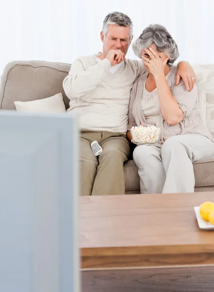 Зрелая пара смотрит телевизор в своей гостиной — стоковое фото