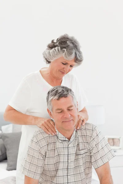 Rentnerin gibt ihrem Mann zu Hause eine Massage — Stockfoto