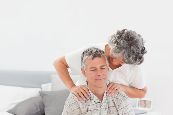Συνταξιούχος γυναίκα δίνει ένα μασάζ στον άντρα στο σπίτι — Φωτογραφία Αρχείου