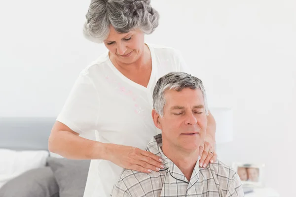 Mulher aposentada fazendo uma massagem ao marido em casa — Fotografia de Stock