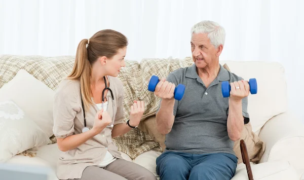 Lovely nurse helping her patient to do exercises — Stock Photo, Image