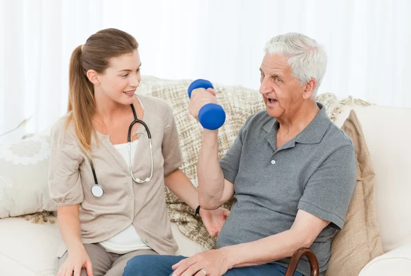 Lovely nurse helping her patient to do exercises — Stock Photo, Image