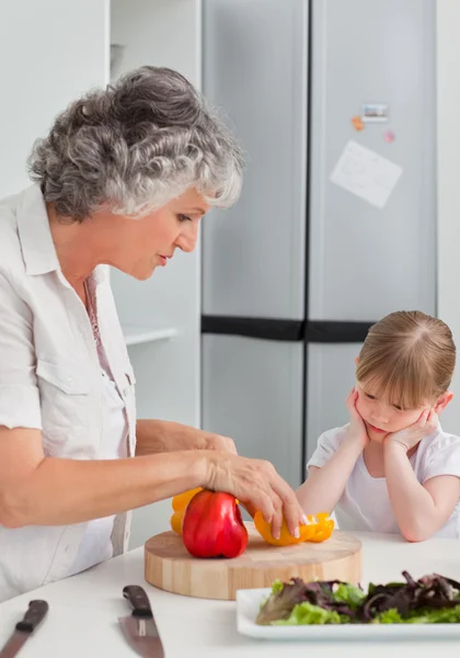 Kleines Mädchen schaut ihre Großmutter an, die kocht — Stockfoto