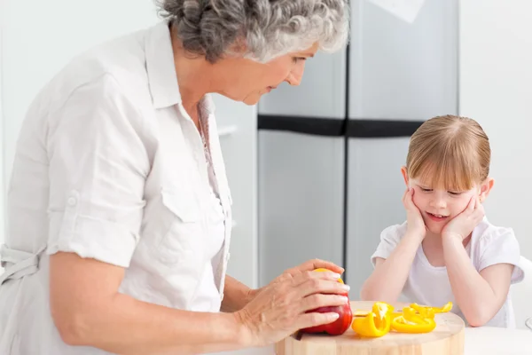 Kleines Mädchen schaut ihre Großmutter an, die kocht — Stockfoto