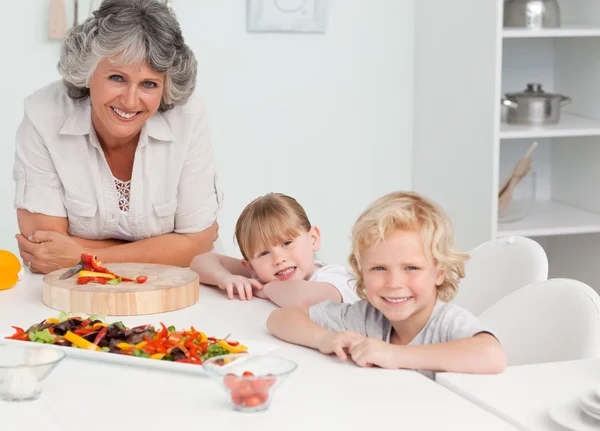 Children cooking with their grandmother at home — Stock Photo, Image