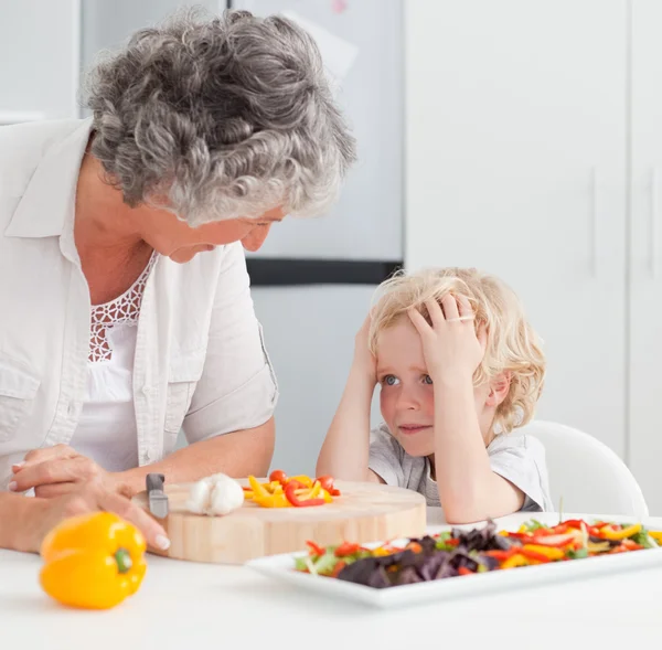Kleiner Junge sieht Großmutter beim Kochen zu Hause zu — Stockfoto